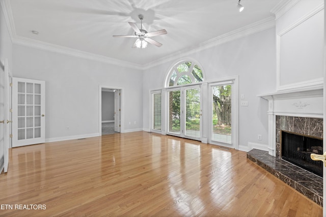 unfurnished living room with a high end fireplace, light wood-style flooring, ornamental molding, and ceiling fan