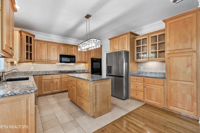 kitchen with a sink, light tile patterned flooring, a kitchen island, black appliances, and tasteful backsplash