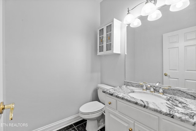 half bathroom featuring baseboards, vanity, and toilet