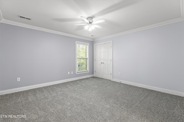 carpeted empty room featuring a ceiling fan, baseboards, crown molding, and visible vents