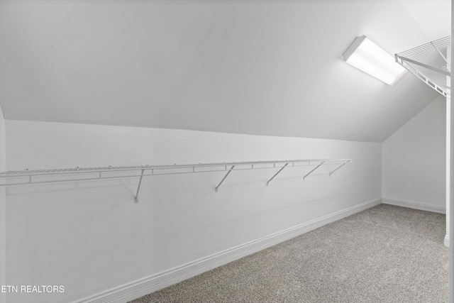 spacious closet featuring light colored carpet and vaulted ceiling