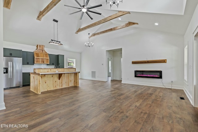 kitchen with stainless steel fridge, high vaulted ceiling, a glass covered fireplace, open floor plan, and beamed ceiling