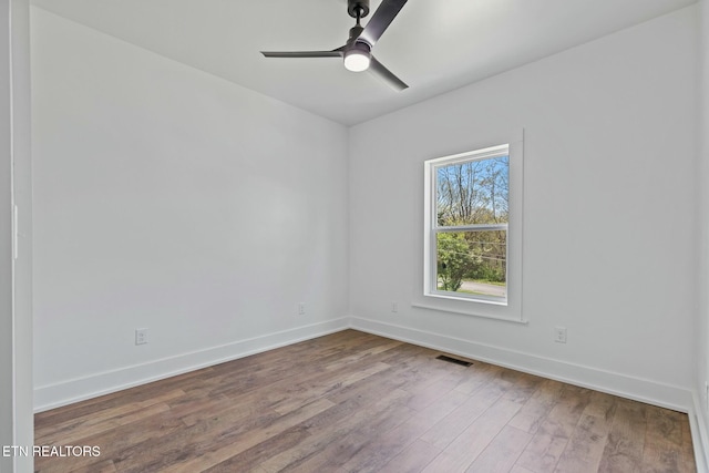 unfurnished room featuring baseboards, ceiling fan, wood finished floors, and visible vents