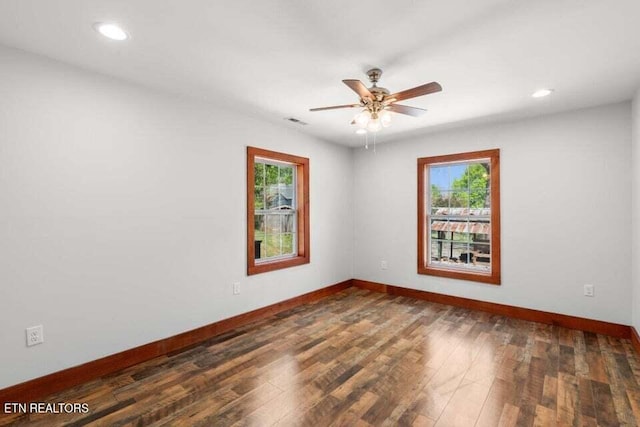 spare room featuring wood finished floors, a healthy amount of sunlight, and baseboards