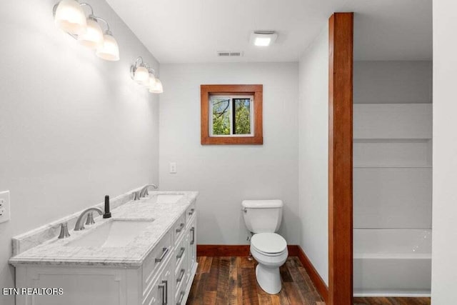 full bath featuring a sink, double vanity, toilet, visible vents, and wood finished floors