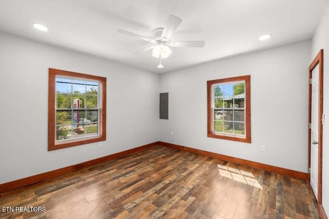 spare room featuring recessed lighting, a healthy amount of sunlight, baseboards, and dark wood-style flooring
