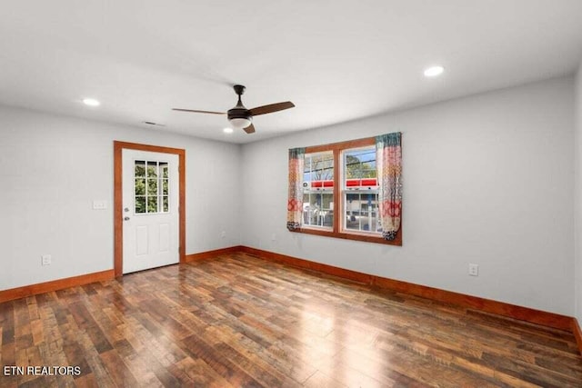 spare room with wood finished floors, a ceiling fan, and baseboards