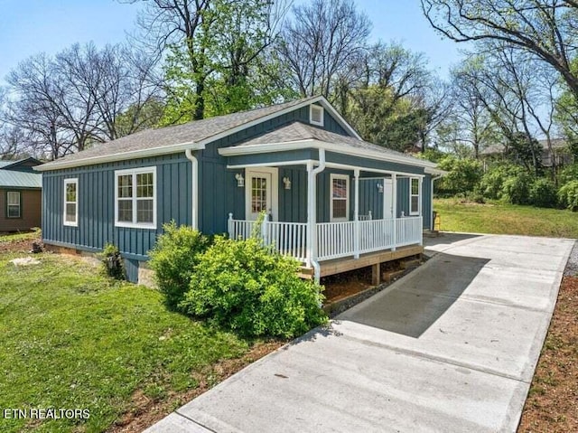bungalow-style house with board and batten siding, a front lawn, and covered porch