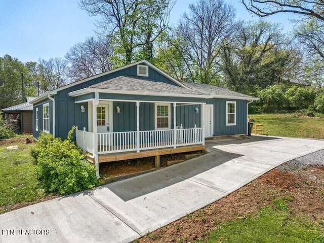 bungalow with board and batten siding, roof with shingles, covered porch, and driveway