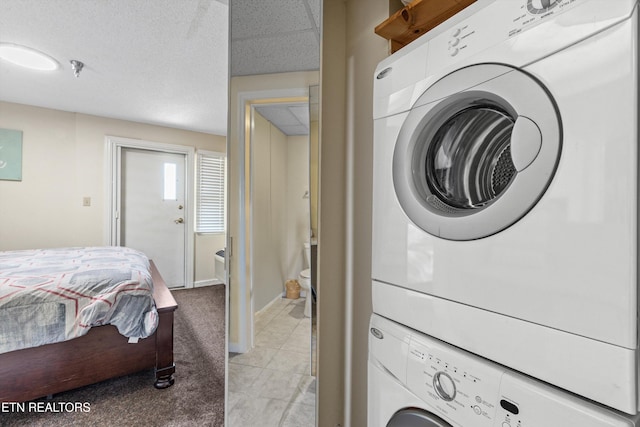 laundry area with baseboards, stacked washing maching and dryer, laundry area, and light colored carpet