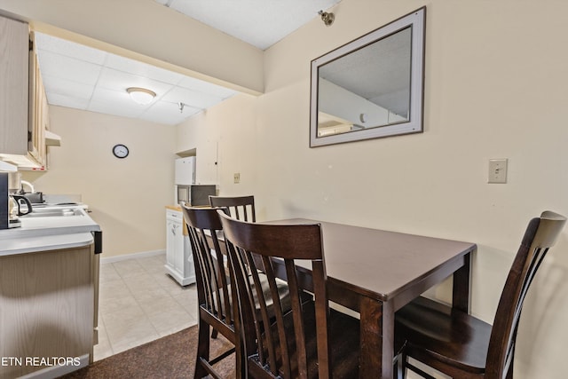 dining room with a paneled ceiling, baseboards, and light tile patterned floors