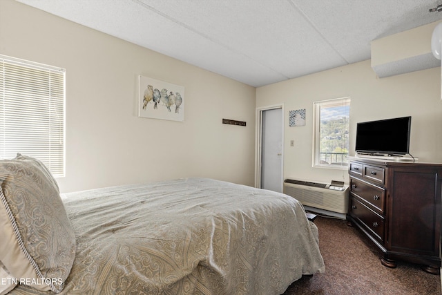 bedroom with dark colored carpet and a wall unit AC