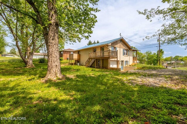 537 Wilson St, Newport, TN 37821 - back of property with a wooden deck, a yard, an attached garage, and stairway