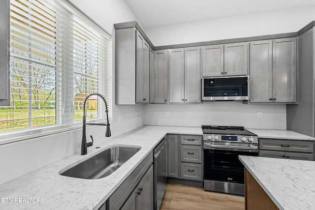103 E Main St, Englewood, TN 37329 - kitchen with a sink, appliances with stainless steel finishes, light wood-style floors, gray cabinetry, and light stone countertops