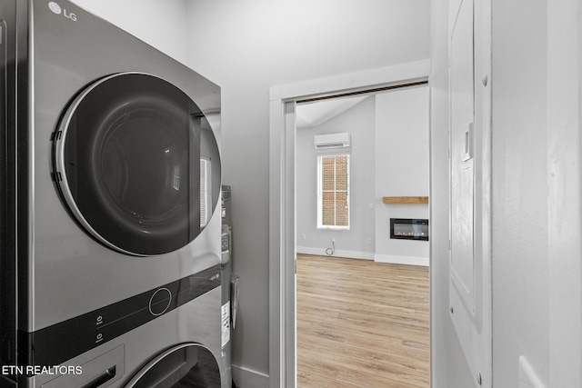 103 E Main St, Englewood, TN 37329 - laundry room with laundry area, a glass covered fireplace, a wall mounted AC, wood finished floors, and stacked washer and clothes dryer
