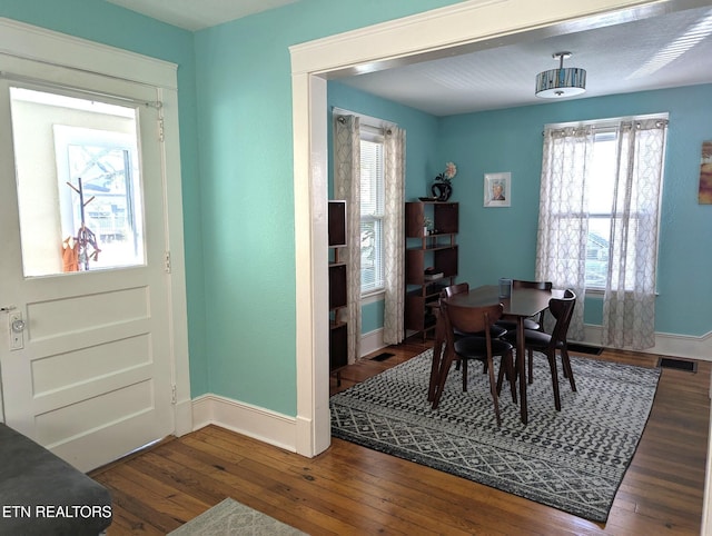 dining area with baseboards, a healthy amount of sunlight, wood-type flooring, and visible vents