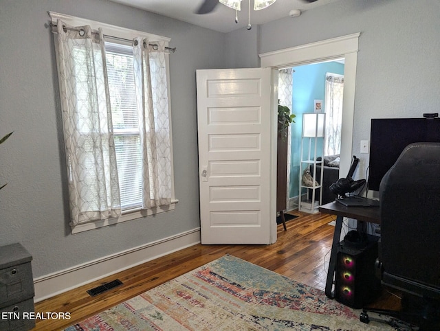 office space featuring wood finished floors, ceiling fan, baseboards, and visible vents