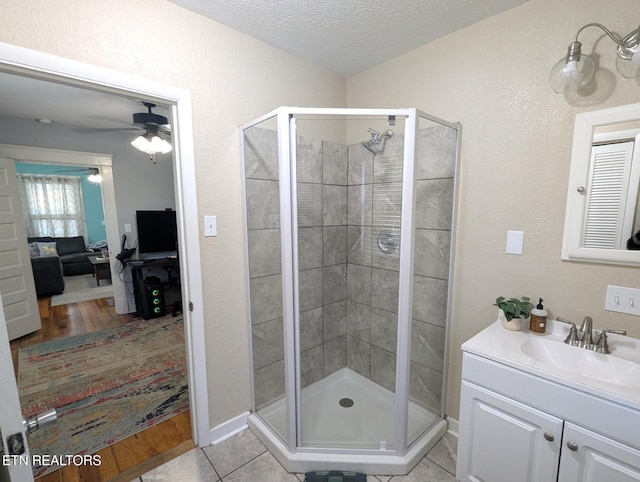 bathroom featuring a shower stall, a textured ceiling, vanity, a ceiling fan, and tile patterned flooring
