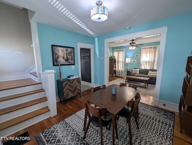 dining space featuring stairs, baseboards, a ceiling fan, and wood finished floors