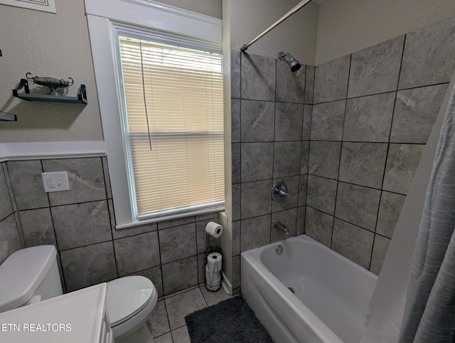 bathroom with tile patterned flooring, shower / bathtub combination with curtain, tile walls, and toilet