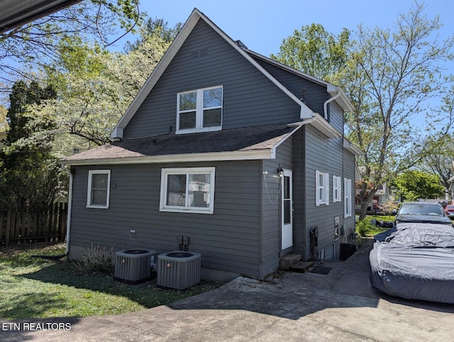 exterior space featuring entry steps, cooling unit, fence, and a shingled roof