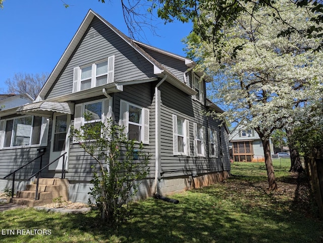 view of home's exterior featuring entry steps, fence, and a lawn