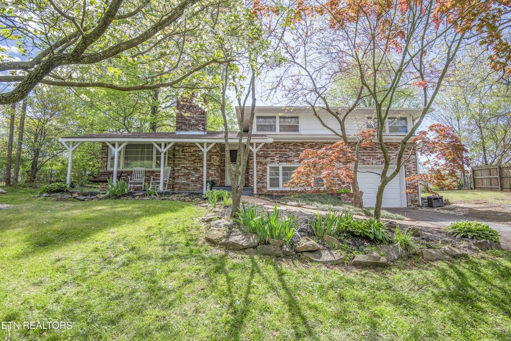 view of front of house with a chimney, an attached garage, aphalt driveway, a porch, and a front yard