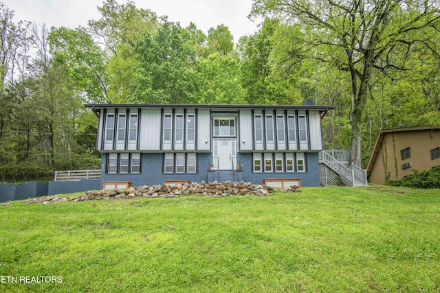 view of front facade featuring stairway, fence, brick siding, and a front yard