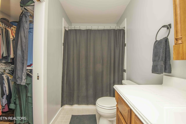 bathroom featuring toilet, tile patterned flooring, a shower with shower curtain, vanity, and a walk in closet
