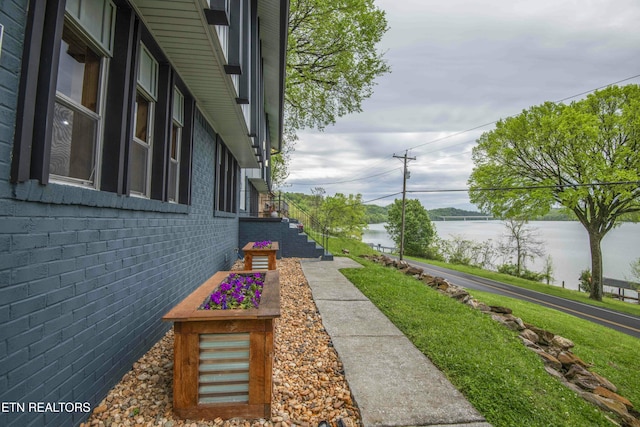 view of property exterior with brick siding and a water view