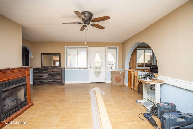 foyer featuring arched walkways, wood finished floors, ceiling fan, and baseboards