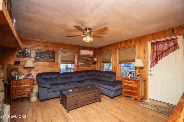 living area with wooden walls, ceiling fan, a wall mounted AC, and wood finished floors