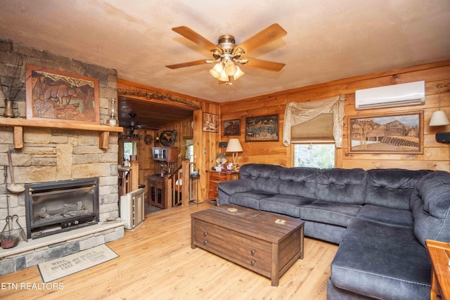 living area with a wall mounted air conditioner, ceiling fan, a fireplace, wood finished floors, and wood walls