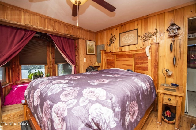 bedroom with wood walls, wood finished floors, and electric panel