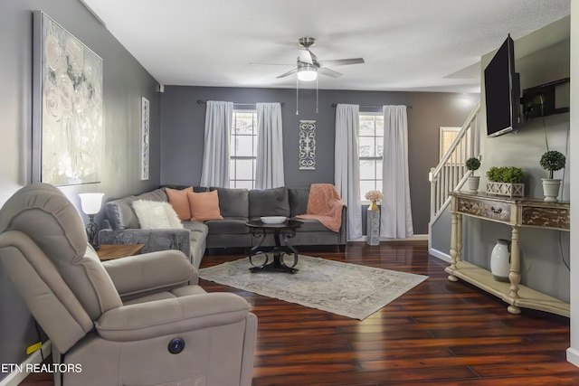 living area with baseboards, a ceiling fan, wood finished floors, and stairway