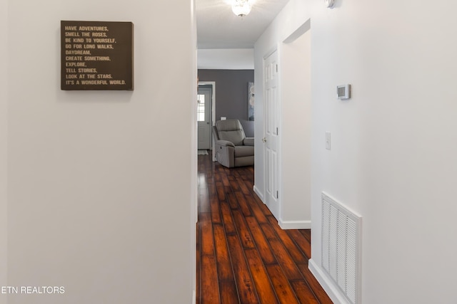 hallway featuring baseboards, wood finished floors, and visible vents