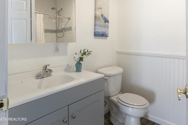 full bath with wainscoting, vanity, curtained shower, and toilet