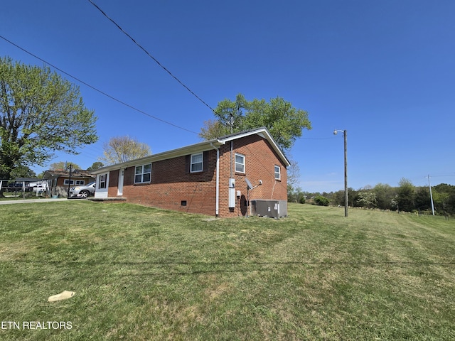 view of property exterior featuring brick siding, crawl space, central AC, and a lawn