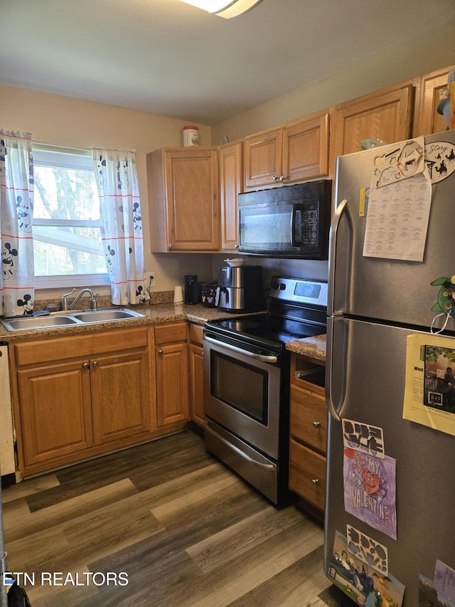 kitchen featuring a sink, wood finished floors, and stainless steel appliances