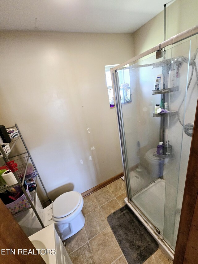 bathroom featuring toilet, a stall shower, baseboards, and tile patterned floors
