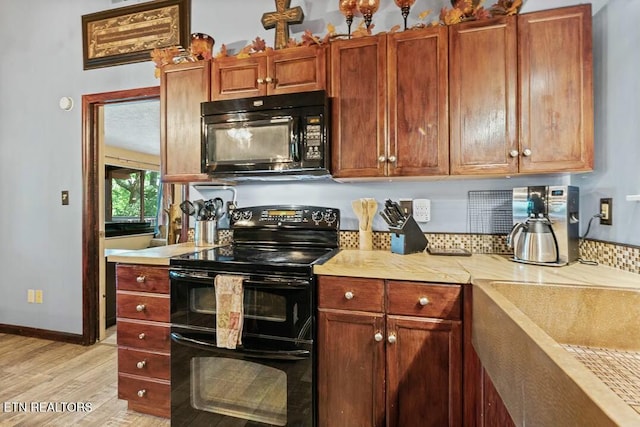 kitchen with baseboards, light wood-type flooring, light countertops, and black appliances