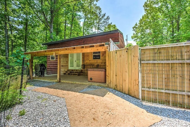 view of outbuilding featuring entry steps, french doors, and fence