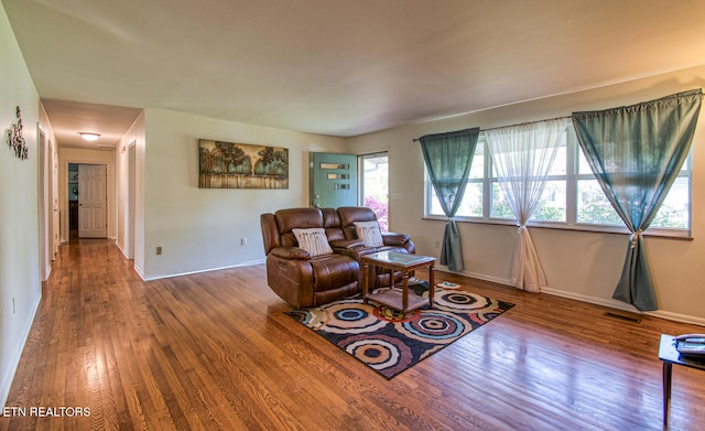 living area featuring wood finished floors, visible vents, and baseboards