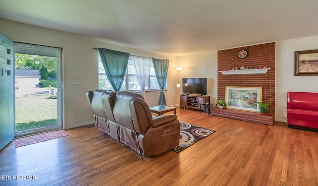 living area with baseboards, wood finished floors, and a fireplace