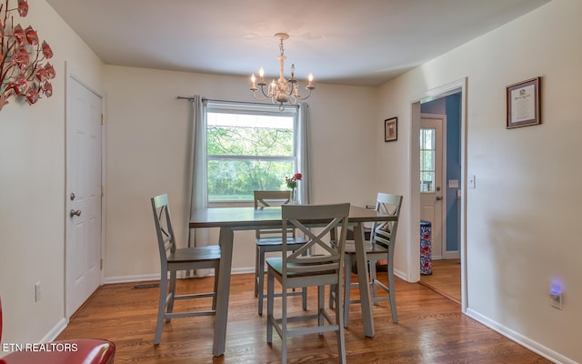 dining room featuring wood finished floors, baseboards, and an inviting chandelier