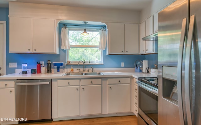 kitchen featuring stainless steel appliances, light countertops, under cabinet range hood, and a sink