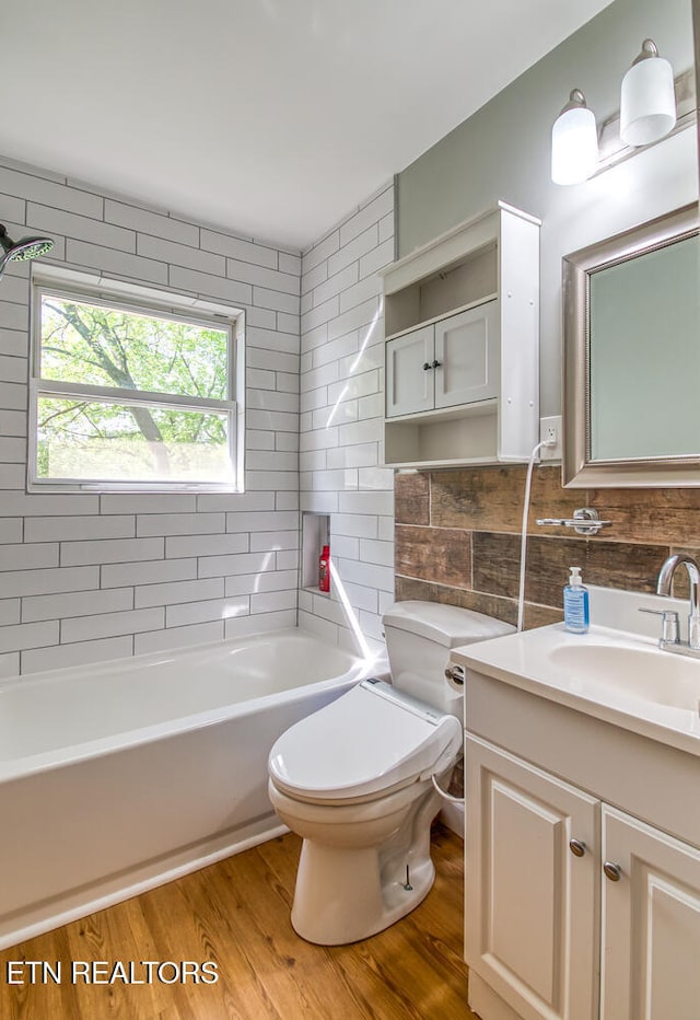 full bathroom with wood finished floors, toilet, vanity, tile walls, and a bathtub