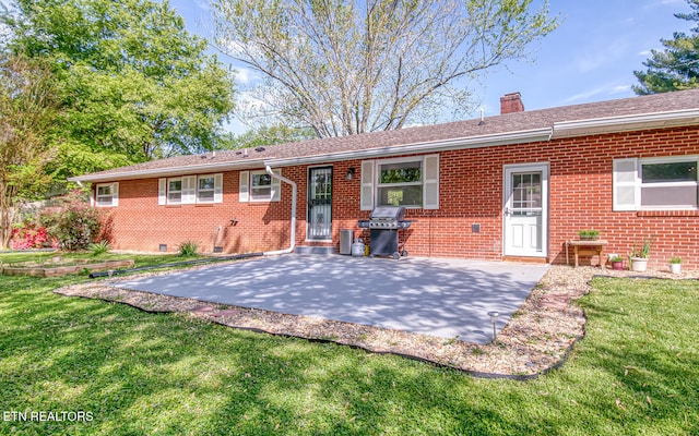 back of house with crawl space, a patio area, a chimney, a lawn, and brick siding