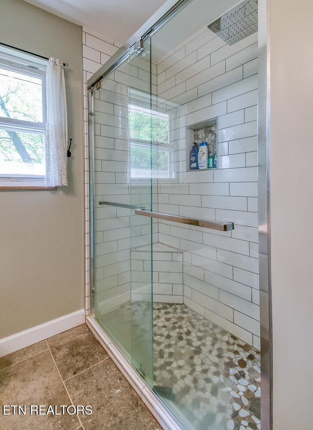 bathroom with a shower stall and baseboards
