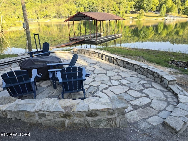 view of patio / terrace with a boat dock, an outdoor fire pit, a forest view, and a water view